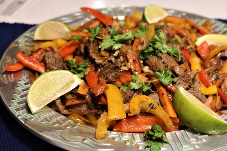 sheet pan fajitas on a platter with roasted peppers and limes