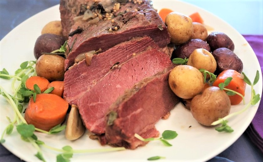 slice corned beef on a white plate with potatoes and carrots