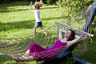 woman relaxing on hammock with child in yard
